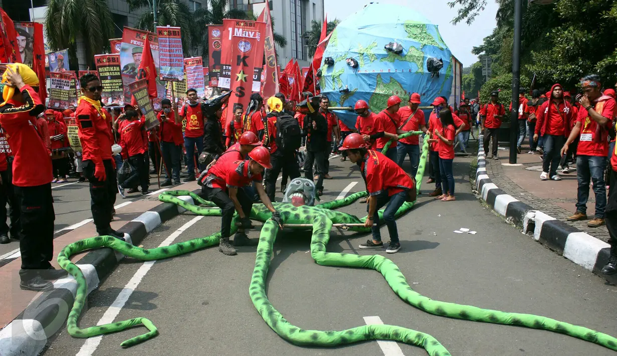 Massa buruh dari KASBI membawa gurita raksasa, bola dunia dan tikus pada peringatan May Day di Bundaran HI, Jakarta, Senin (1/5). Replika gurita itu dianggap simbol penghisap sumber daya alam yang ada di Indonesia. (Liputan6.com/Angga Yuniar)