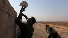 Seorang tentara Irak menggunakan senapan untuk menahan helm sebagai umpan dalam bentrokan dengan militan ISIS di Al-Qasar, Tenggara Mosul, Irak (28/11). (REUTERS/Goran Tomasevic)