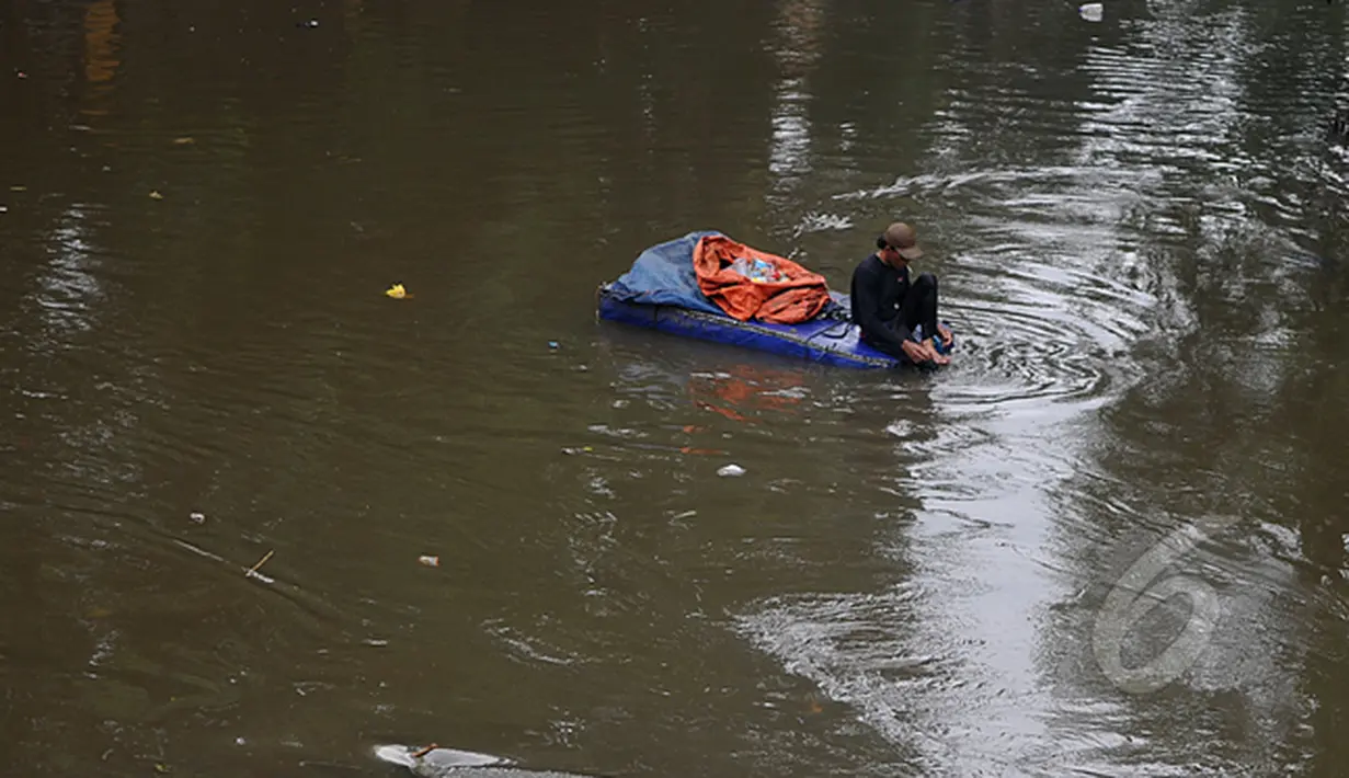 Masih banyak warga bantaran kali Ciliwung Jakarta yang memanfaatkan air kali untuk kehidupan sehari - hari. Tampak seorang pemulung mengumpulkan sampah plastik yang ada di kali Ciliwung Jakarta, Jumat (20/2/2015). (Liputan6.com/JohanTallo)