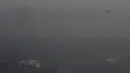 Sebuah pesawat melintas di tengah kabut asap tebal yang menyelimuti Beijing, Cina, 2 Januari 2017. Kabut tebal ini membuat sejumlah warga mengunakan masker saat beraktivitas. (Reuters/Jason Lee)