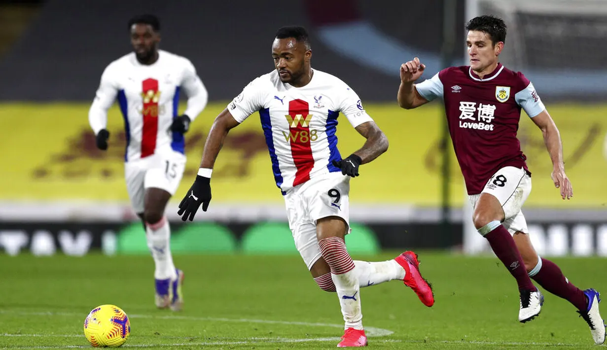 Pemain Crystal Palace Jordan Ayew (kiri) dan pemain Burnley Ashley Westwood mengejar bola pada pertandingan Liga Premier Inggris di Stadion Turf Moor, Burnley, Inggris, Senin (23/11/2020). Burnley menang dengan skor 1-0. (Jan Kruger/Pool via AP)