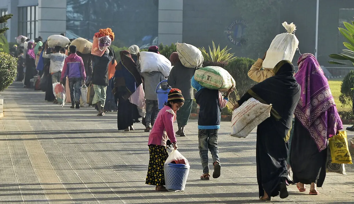 Pengungsi Rohingya berjalan dengan barang-barang mereka untuk dipindahkan ke Pulau Bhasan Char di Chattogram, Bangladesh, Jumat (29/1/2021). Kelompok HAM menyerukan agar Bangladesh menghentikan relokasi ribuan pengungsi Rohingya ke Pulau Bhasan Char. (AP Photo/Azim Aunon)