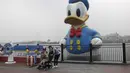 Wisatawan berswafoto di depan patung Donald Duck di taman hiburan Disneyland, Shanghai, China, Senin (11/5/2020). Saat ini Disneyland Shanghai hanya menerima pengunjung kurang dari 24 ribu orang, atau 30 persen dari kapasitas harian. (AP Photo/Chen Si)