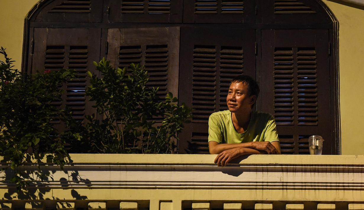 Gambar pada 2 September 2021 menunjukkan seorang pria sedang minum di balkon rumahnya di Hanoi, Vietnam, selama lockdown Covid-19. Menghadap ke jalan yang sepi, balkon kecil mereka menjadi saksi bisu terkait aktivitas yang dilakukan oleh masing-masing keluarga. (Nhac NGUYEN/AFP)