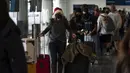 Mengenakan topi Sinterklas, Caitlin Banford mengantre untuk check-in penerbangannya ke Washington di Bandara Internasional Los Angeles, Senin (20/12/2021). Departemen Kesehatan Masyarakat Los Angeles County melaporkan lebih dari 3.500 kasus baru COVID-19 pada hari Minggu. (AP Photo/Jae C.Hong)