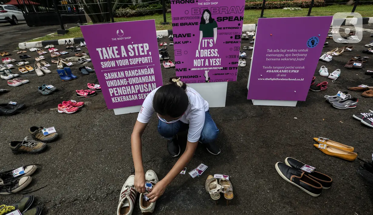 Pegiat komnas perempuan merapikan sepatu saat aksi diam 500 Langkah Awal Sahkan RUU PKS di depan gedung DPR, Jakarta, Rabu (25/11/2020). Dalam aksinya mereka menyusun sepatu sebagai simbol "semua peduli, semua terlindungi, stop sexual violence". (Liputan6.com/Johan Tallo)