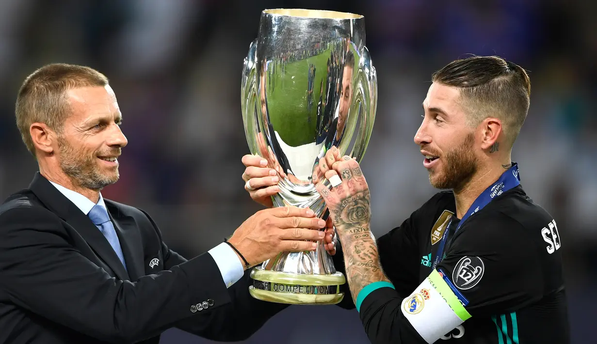 Presiden UEFA Aleksander Ceferin memberikan trofi Piala Super Eropa kepada bek Real Madrid, Sergio Ramos usai timnya menumbangkan Manchester United (MU) di Skopje, Macedonia, Selasa (8/8). Real Madrid mengalahkan MU dengan skor 2-1 (Dimitar DILKOFF / AFP)