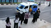 Para calon penumpang antre menunggu giliran untuk naik transportasi layanan angkutan umum JakLingko di Stasiun Klender Baru, Pondok Kopi, Jakarta, Senin (19/2/2024). (merdeka.com/Imam Buhori)