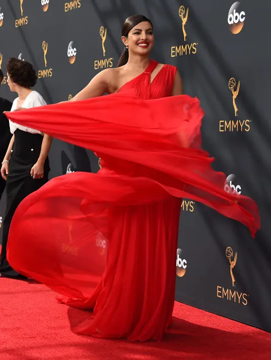 Aktris Bollywood Priyanka Chopra mengibaskan gaunnya ketika berpose di karpet merah Emmy Awards 2016 di Microsoft Theater, Los Angeles, Minggu (18/9). Priyanka mencuri perhatian dengan gaun merah merona yang menjuntai ke lantai. (AFP PHOTO/Robyn Beck)