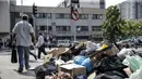 Orang-orang berjalan melewati tumpukan sampah yang diakibatkan pemogokan petugas sampah di Santiago (14/11/2019). Demo yang semakin keras juga disertai aksi mogok nasional termasuk petugas sampah di negara kaya minyak di Amerika Selatan tersebut.  (AFP/Javier Torres)