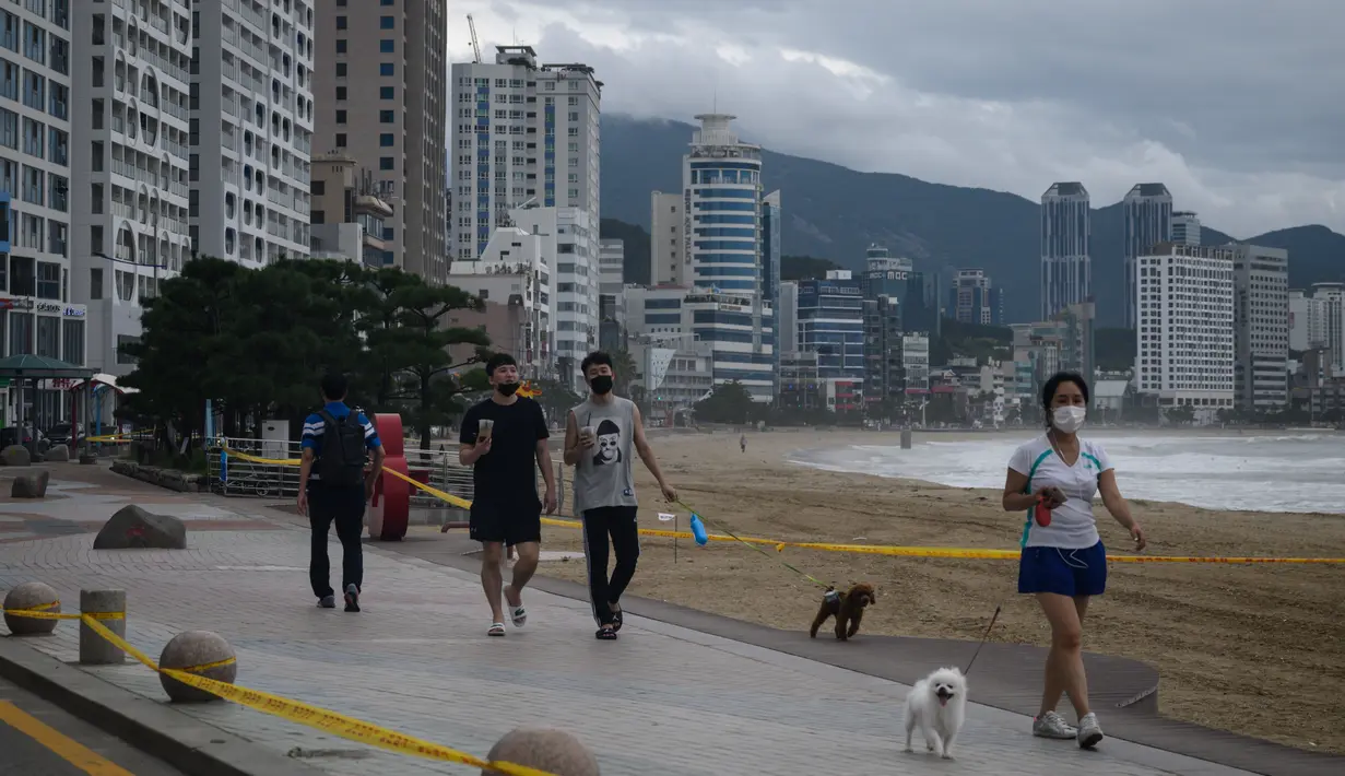 Orang-orang berjalan di sepanjang kawasan pejalan kaki di pantai Gwangalli yang ditutup di Busan (2/9/2020). Penerbangan dihentikan di Korea Selatan dan peringatan badai dikeluarkan di kedua sisi semenanjung Korea sebagai topan yang diperkirakan akan menjadi salah satu yang terkuat. (AFP/Ed Jones)