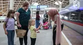 Petugas perempuan Kereta Cepat Whoosh mengenakan kebaya sambil membagikan bunga kepada calon penumpang di Stasiun Halim Whoosh, Jakarta, Senin (21/4/2025). (Liputan6.com/Angga Yuniar)