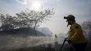 Seorang petugas pemadam kebakaran sukarela menggunakan tusukan dari selang untuk membasahi sisa-sisa gubuk yang terbakar selama kebakaran semak di lingkungan Banco San Miguel di Asuncion, Paraguay (18/1/2022). (AP Photo/Jorge Saenz)