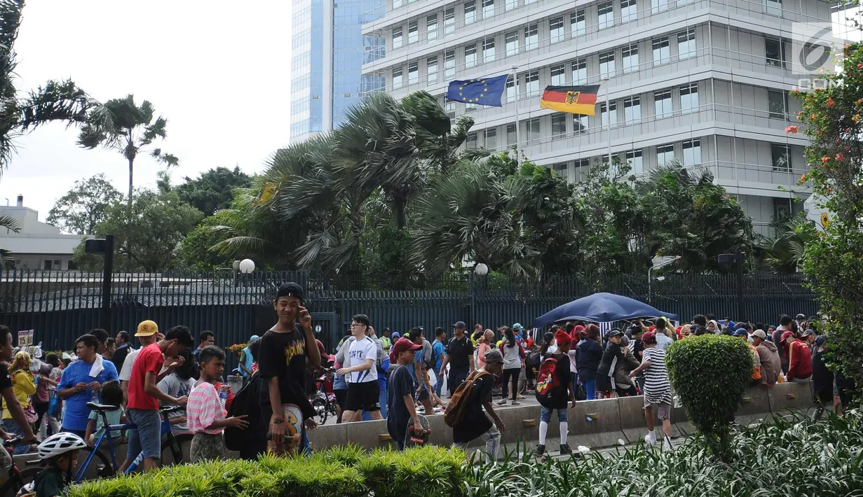 Bendera dan pohon di Kedutaan Besar terhembus angin kencang yang terjadi di sekitar Bundaran Hotel Indonesia, Jakarta, Minggu (26/11). Angin kencang dan gerimis terjadi saat kegiatan Hari Bebas Kendaraan, Minggu pagi. (Liputan6.com/Helmi Fithriansyah)