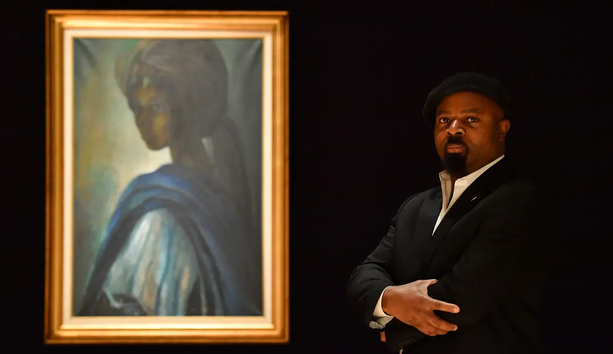 Novelis Nigeria, Ben Okri berpose dekat lukisan seorang putri Nigeria bernama Tutu di rumah lelang Bonhams, London pada 7 Februari 2018. Lukisan yang kerap disebut ‘Mona Lisa dari Afrika’ itu berhasil terjual lebih dari 22 miliar rupiah (BEN STANSALL/AFP)