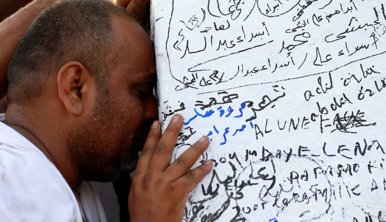 Seorang jemaah tampak berdoa di batu yang penuh coretan di puncak Jabal Rahmah, Arafah, yang penuh coretan di Mekah, Minggu (11/9). Bukit yang dikenal sebagai Bukit Kasih Sayang itu menjadi pusat prosesi ibadah haji, wukuf. (REUTERS/Ahmed Jadallah)
