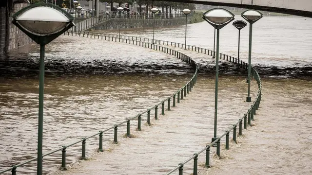 Seorang pria melihat keluar dari balkonnya saat mobil terendam di dekat Sungai Meuse saat banjir di Liege, Belgia, Kamis, 15 Juli 2021.  (Foto AP/Valentin Bianchi)