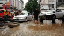 Petugas mengevakuasi mobil mewah di Jalan Kemang Raya, Minggu (28/8). Sejumlah kendaraan terendam air di kawasan Kemang Raya pasca hujan deras di Jakarta pada Sabtu (27/8). (Liputan6.com/Helmi Fithriansyah)