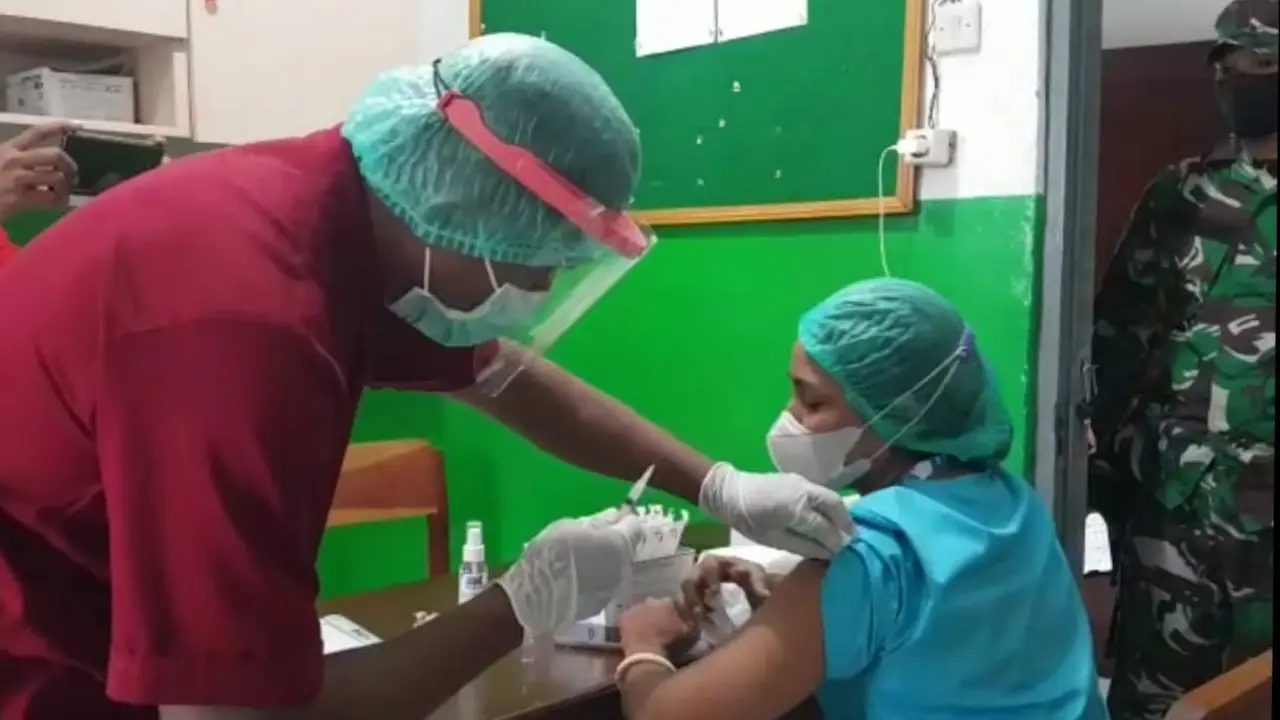 Seorang Nakes di Kabupaten Sikka, takut saat jarum suntik vaksin covid-19 akan ditusuk ke lengannya. (Liputan6.com/Dionisius Wilibardus)