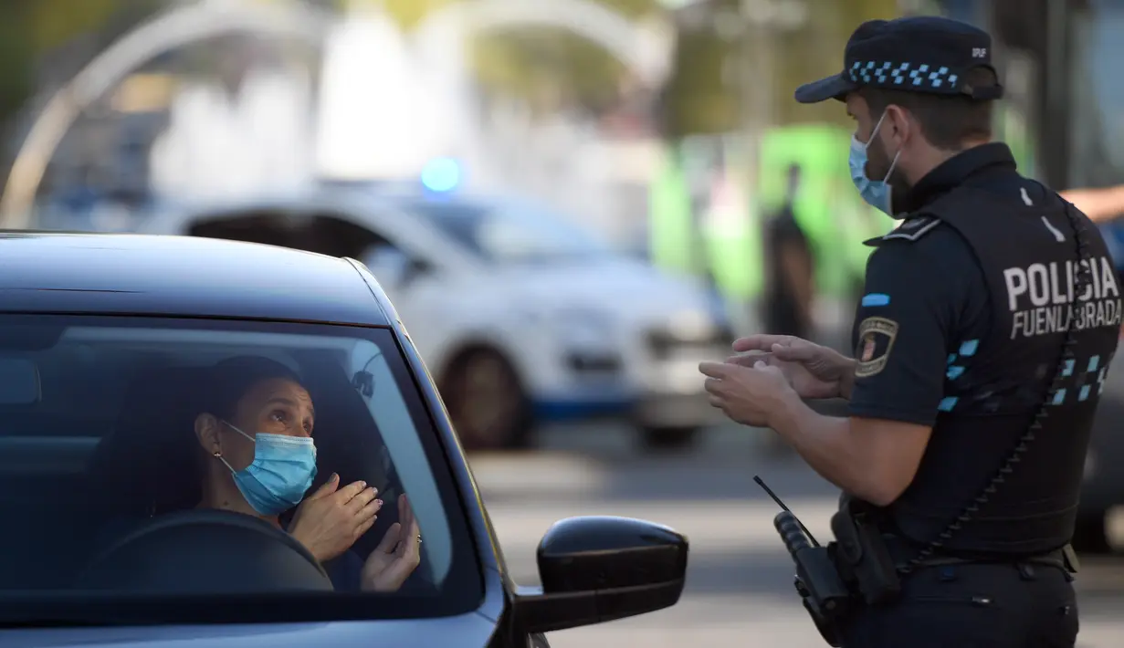 Petugas polisi setempat mengontrol pergerakan orang di sebuah pos pemeriksaan lalu lintas di kota Fuenlabrada yang tertutup sebagian, di wilayah Madrid (22/9/2020). Penguncian dilakukan akibat infeksi virus melonjak. (AFP/Oscar Del Pozo)