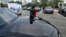 Petugas membersihkan mobil BMW i7 dan i5 di komplek GBK, Senayan, Jakarta, Jumat (3/5/2024). (Liputan6.com/Angga Yuniar)