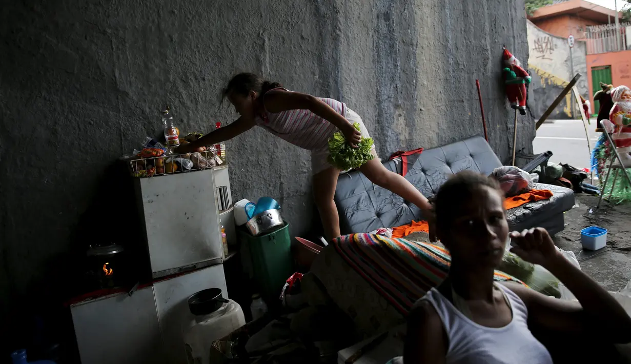 Seorang anak mengambil makanan dirumahnya yang hanya berlindung jembatan di Sao Paulo, Brasil, (18/12). Mereka adalah keluarga tunawisma yang tinggal di bawah jembatan. (REUTERS/Nacho Doce)