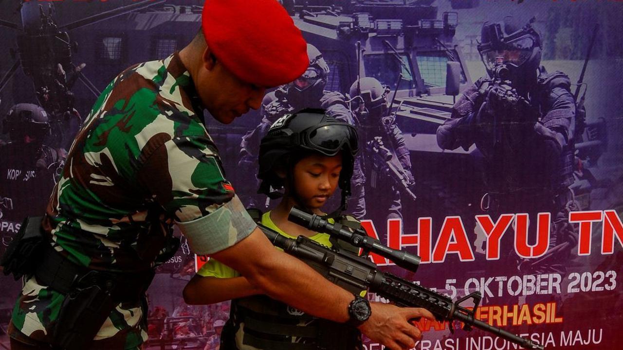 Seorang anak mencoba memegang senapan serbu  yang ditampilkan dalam pameran tersebut.