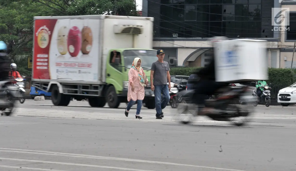 Pejalan kaki dengan hati-hati menyeberangi jalan di persimpangan Terminal Pulo Gadung, Jakarta, Rabu (5/9). Tiadanya jembatan penyeberangan orang (JPO) dan lampu merah mengancam keselamatan pejalan kaki dan pengendara. (Merdeka.com/Iqbal Nugroho)