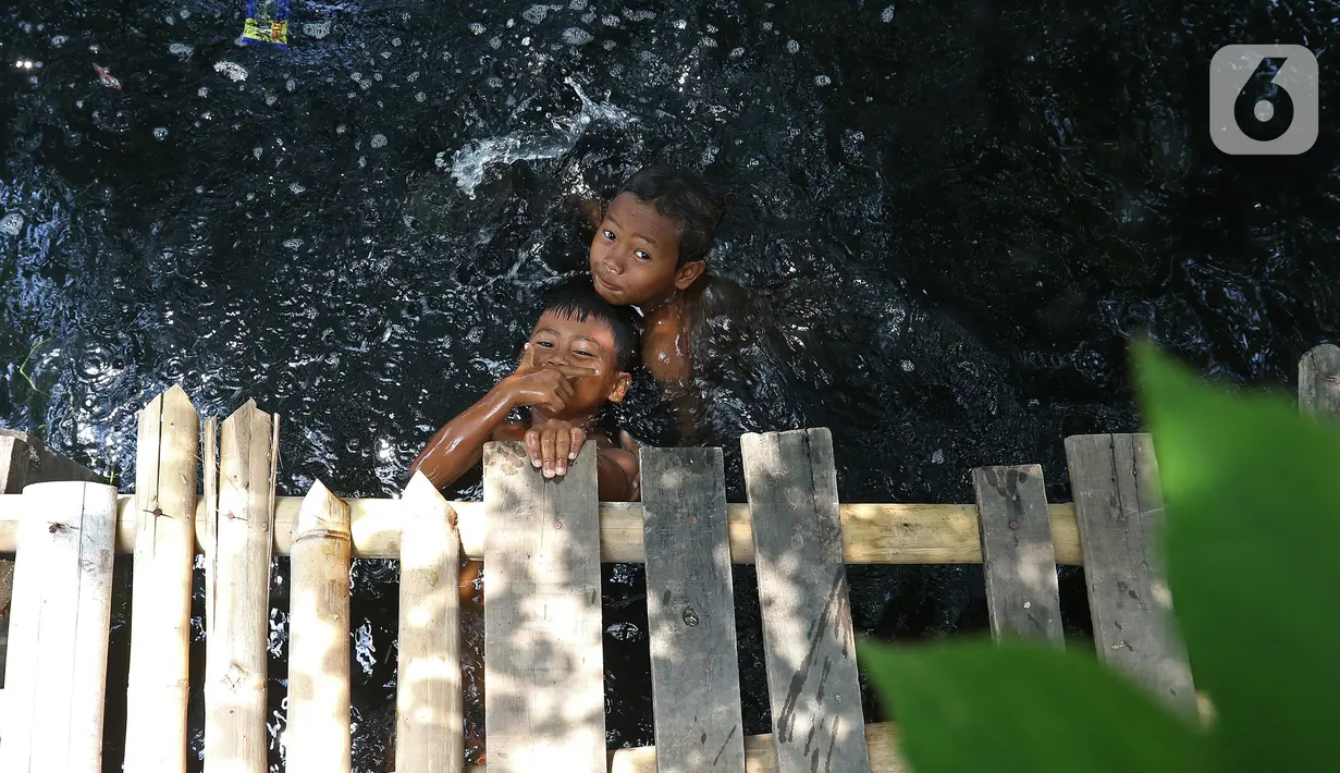 Anak-anak berenang di Kali Cilemahabang yang menghitam di kawasan Karangbahagia, Kabupaten Bekasi, Jawa Barat, Selasa (7/9/2021). Menurut warga sekitar, Kali Cilemahabang menghitam akibat tercemar limbah industri sejak lima tahun lalu. (Liputan6.com/ Herman Zakharia)