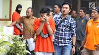 Tersangka pembunuhan wanita yang ditemukan tewas di dalam lemari digiring petugas jelang memeragakan adegan peristiwa di TKP di kawasan Mampang, Jakarta, Jumat (23/11). 13 adegan dilakukan para tersangka. (Liputan6.com/Helmi Fithriansyah)