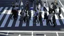 Orang-orang mengenakan masker untuk membantu mencegah penyebaran virus corona berjalan di sepanjang penyeberangan pejalan kaki di Tokyo (21/4/2021). Ibukota Jepang mengonfirmasi lebih dari 840 kasus virus corona baru pada hari Rabu. (AP Photo/Eugene Hoshiko)