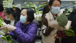 Pelanggan mengenakan masker, membeli sayuran segar di toko pasar basah di Hong Kong, Rabu, 9 Februari 2022. Hong Kong memberlakukan langkah-langkah jarak sosial yang paling ketat untuk mempertahankan kebijakan nol COVID-19 di tengah lonjakan kasus yang dipicu Varian Omicron. (AP Photo/Vincent Yu)