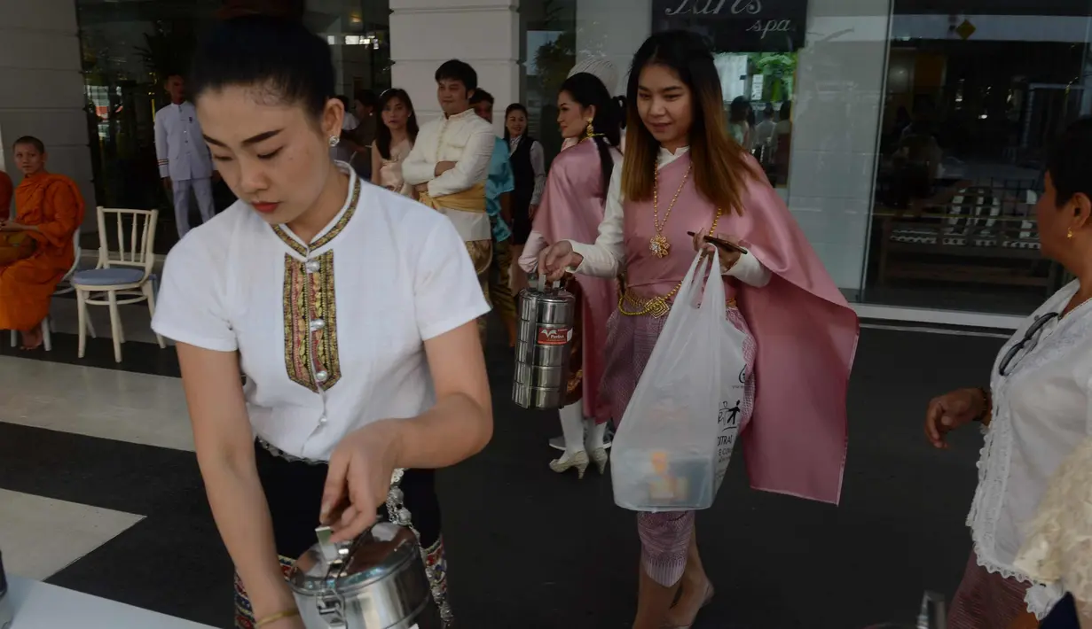 Para pekerja wanita mengenakan kostum tradisional mempersiapkan persembahan bagi para biksu Budha selama upacara keagamaan sebagai persiapan festival tahun baru Songkran di luar kantor di Bangkok, Thailand (9/4). (AFP Photo/Romeo Gacad)