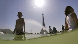 Turis dan warga masuk ke dalam kolam Trocadero Fountains (air mancur Trocadero) dekat Menara Eiffel di Paris, Kamis (25/7/2019). Gelombang panas di Eropa mencapai puncaknya, bahkan suhu di ibu kota Prancis mencapai di atas 41 derajat Celcius. (Dominique FAGET / AFP)