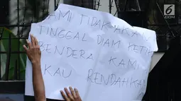 Salah satu peserta aksi menempelkan kertas pesan saat berunjuk rasa di depan Kedubes Malaysia, Jakarta, Senin (21/8). Aksi ini terkait kasus terbaliknya bendera Merah Putih pada buku panduan pelaksanaan SEA Games 2017. (Liputan6.com/Helmi Fithriansyah)