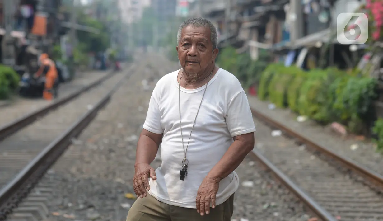 Penjaga perlintasan kereta api tanpa palang pintu, Wandi, menjaga perlintasan di Kawasan Petamburan, Jakarta, Jumat (4/6/2021). Sudah 10 tahun, Bapak Wandi menjaga palang pintu perlintasan kereta api yang kerap dilintasi oleh  pengguna jalan untuk menyeberang. (merdeka.com/Imam Buhori)