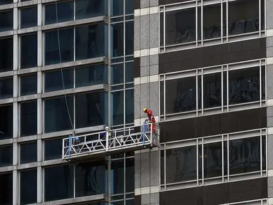 Pekerja membersihkan kaca gedung bertingkat di kawasan Sudirman Central Business District (SCBD), Jakarta, Senin (8/6/2020). Hampir tiga bulan kebijakan work from home (WFH) akibat pandemi COVID-19, banyak gedung bertingkat tidak terawat hari ini mulai dibersihkan. (merdeka.com/Dwi Narwoko)