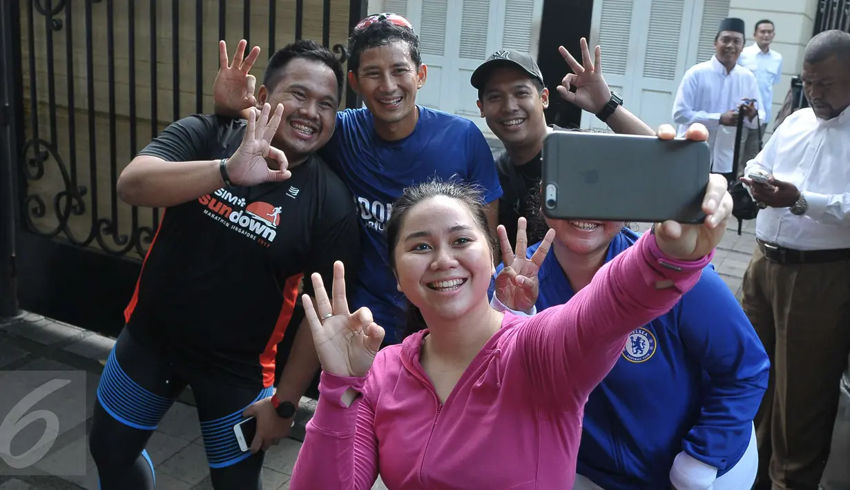 Cawagub DKI, Sandiaga Uno berswafoto seusai lari mengelilingi TPS di sekitar rumahnya di Selong, Kebayoran Baru, Jakarta, Rabu (19/4). Sandiaga berolahraga sebelum memberikan hak suaranya dalam Pilkada DKI 2017 putaran kedua. (Liputan6.com/Helmi Afandi)