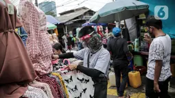 Pedagang menggunakan alat pelindung wajah (Face Shield) saat melayani pembeli di Kawasan Tanah Abang, Jakarta, Senin (18/5/2020). Penggunaan alat pelindung wajah itu sebagai upaya untuk melindungi diri saat berhubungan dengan pembeli dalam pecegahan penyebaran COVID-19. (Liputan6.com/Faizal Fanani)