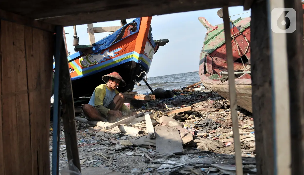 Pekerja menyelesaikan proses perbaikan kapal nelayan di pesisir Marunda, Jakarta, Selasa (22/10/2019). Untuk jasa perbaikan satu buah kapal biasanya dipatok dengan harga Rp 15 juta dalam waktu pengerjaan hingga sebulan. (merdeka.com/Iqbal Nugroho)