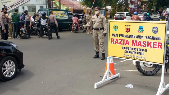Nampak petugas gabungan Satpol PP, TNI-polres Garut, terlihat tengah melakukan razia gabungan dalam penerapan aturan ketat penggunaan maskr di Garut, Jawa Barat.