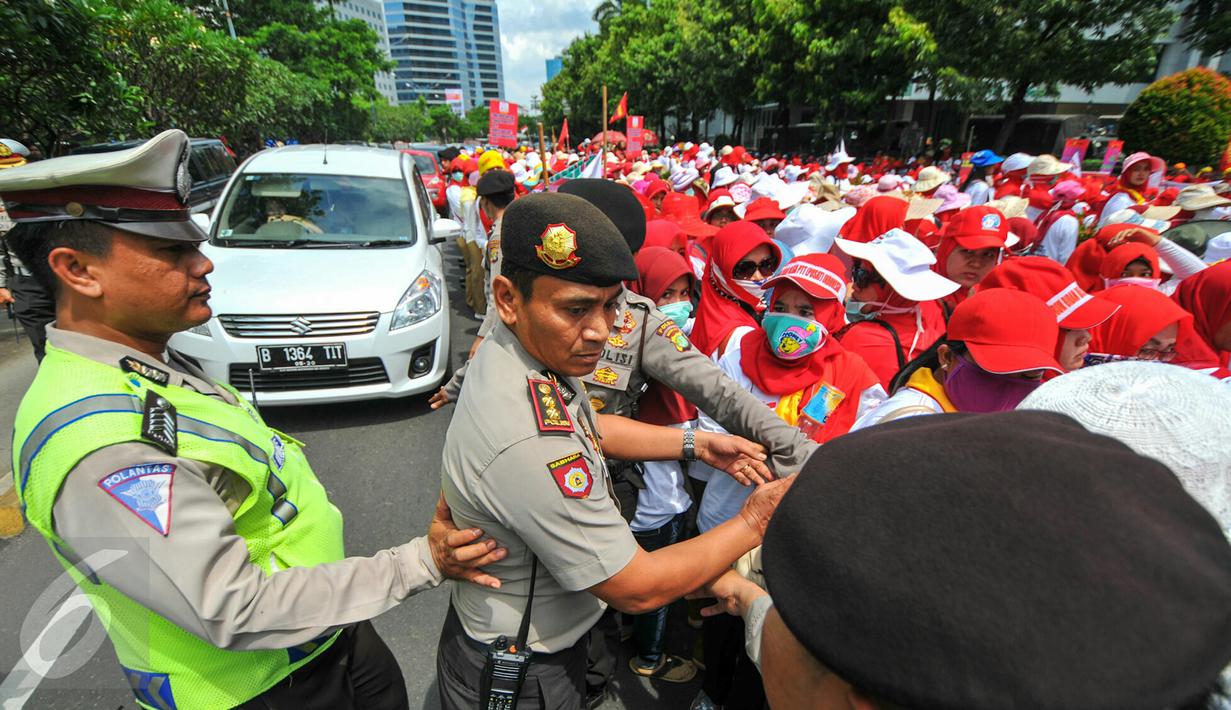 Petugas kepolisian membantu rekannya menertibkan demonstrasi ratusan bidan desa yang menutup akses jalan di depan gedung Kemenkes, Jakarta, Rabu (4/5). Para bidan tersebut menuntut diangkat menjadi pegawai tetap tanpa syarat.  (Liputan6.com/Yoppy Renato)