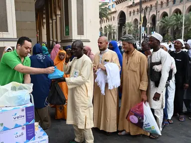 Seorang sukarelawan membagikan paket makanan yang ditawarkan oleh penduduk Makkah kepada para jemaah haji di Kota Suci Makkah, Arab Saudi, 23 Juni 2023. (Sajjad HUSSAIN/AFP)