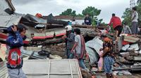 Warga memeriksa reruntuhan bangunan yang rusak akibat gempa bumi di Mamuju, Sulawesi Barat, Sabtu (16/1/2021). Jalan dan jembatan yang rusak, pemadaman listrik, dan kurangnya alat berat menghambat evakuasi setelah gempa bermagnitudo 6,2 SR yang melanda Majene- Mamuju. (AP Photo/Yusuf Wahil)