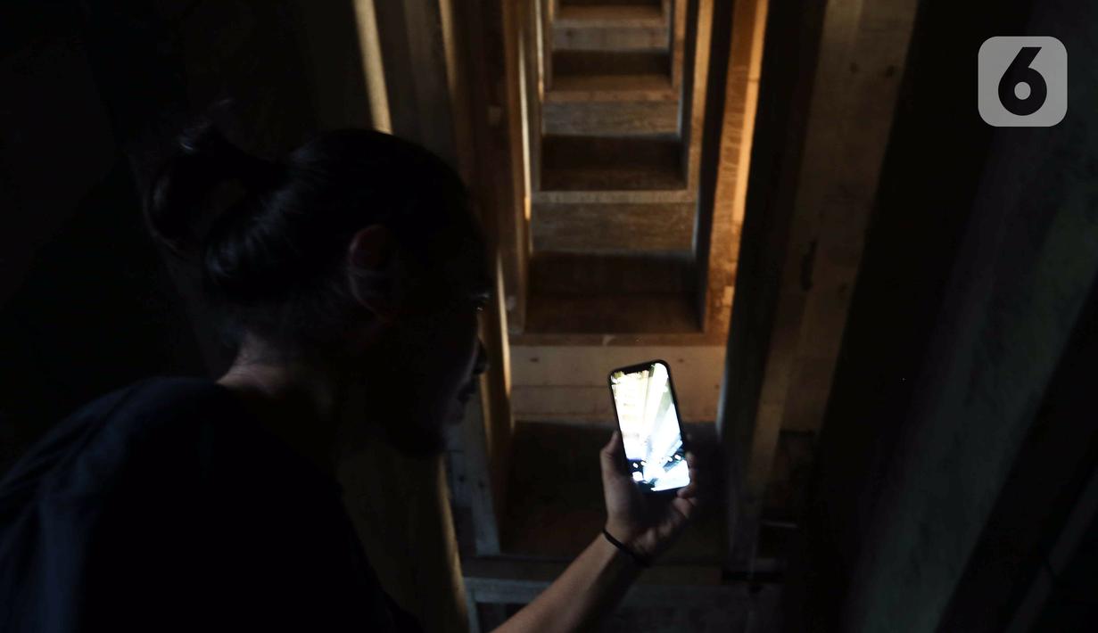 Pengunjung mengambil gambar bangunan rusun yang menjadi lokasi syuting film Pengabdi Setan 2: Communion di kawasan Bekasi, Jawa Barat, Rabu (10/8/2022). Tidak diketahui alasan proyek pembangunan rusun ini terbengkalai. (Liputan6.com/Herman Zakharia)