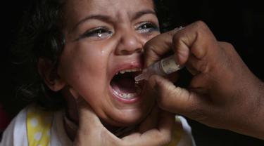 Seorang anak menangis saat diberikan vaksin polio oleh pekerja kesehatan di Lahore, Pakistan, (9/4). Pakistan meluncurkan vaksinasi polio baru, yang bertujuan agar 38,7 juta anak di bawah usia 5 tahun mendapatkan vaksin tersebut. (AP Photo/KM Chaudary)