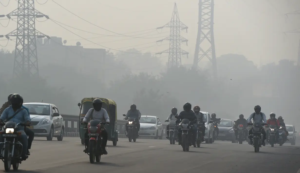 Kendaraan bermotor menembus kabut asap pekat yang menyelimuti jalan di New Delhi, Selasa (12/11/2019). Kabut asap kembali menyelimuti ibu kota India setelah akhir pekan dengan udara cerah dan cuaca yang lebih baik. (Photo by Money SHARMA / AFP)