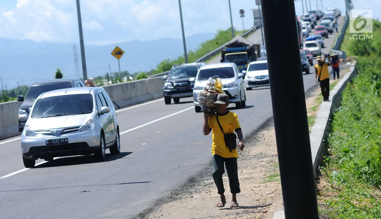 Pedagang makanan ringan asongan jelang Simpang Tiga Keluar Tol Brebes, Jawa Tengah, Sabtu (23/12). Memanfaatkan kepadatan arus libur panjang Natal 2017, pedagang menjajakan dagangan di Simpang Tiga Keluar Tol Brebes. (Liputan6.com/Helmi Fithriansyah)