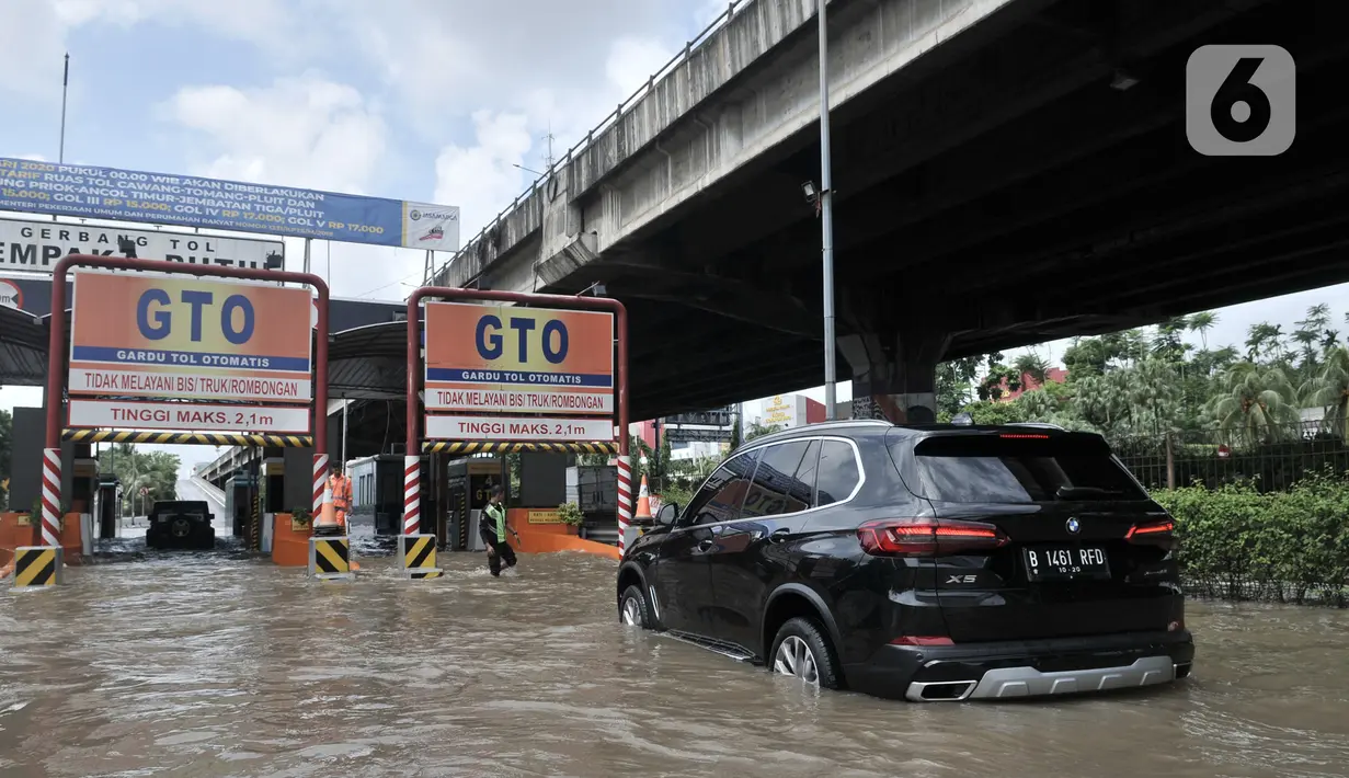Mobil nekat menerobos banjir menuju Gerbang Tol Cempaka Putih, Jakarta, Minggu (23/2/2020). Banjir yang melanda kawasan tersebut menyebabkan Gerbang Tol Cempaka Putih tidak dioperasikan akibat terendam hingga ketinggian mencapai sepinggang orang dewasa. (merdeka.com/Iqbal S. Nugroho)