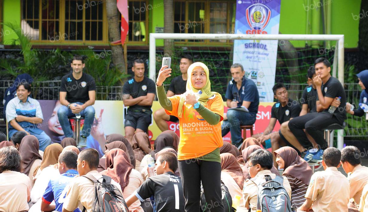 Seorang guru SMAN 3 Kota Malang selfie dengan latar belakang pemain Arema. Sabtu (30/4/2016).(Bola.com/Iwan Setiawan)